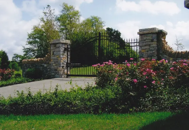 Arched driveway gate with stone columns - Elantra Gate Systems