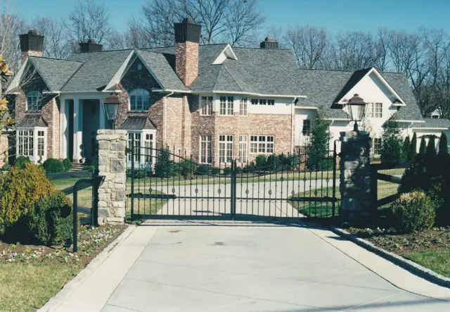 Arched estate gate with lantern-topped stone columns - Elantra Gate Systems