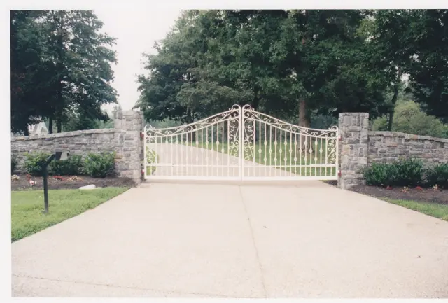 White ornamental scroll gate with stone wall - Elantra Gate Systems